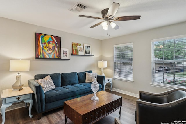living room featuring wood finished floors, visible vents, a ceiling fan, and baseboards