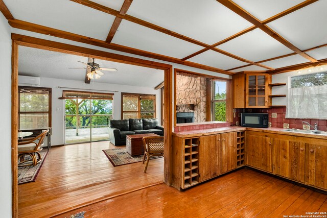 kitchen featuring open shelves, a sink, hardwood / wood-style floors, brown cabinets, and black microwave