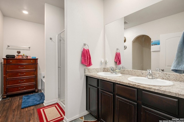 bathroom with wood finished floors, a stall shower, and a sink
