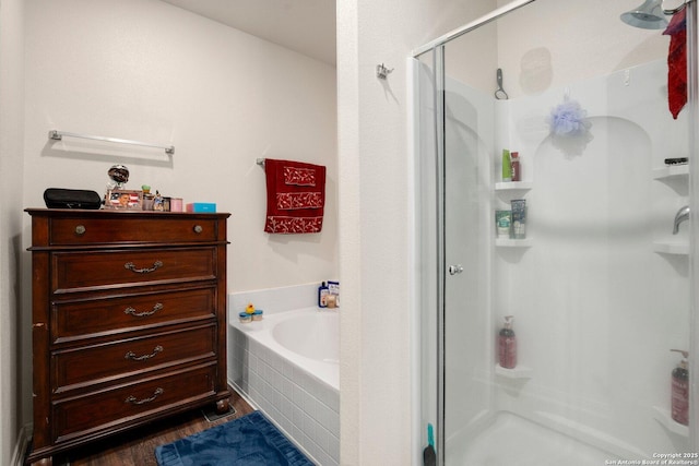 full bathroom featuring a garden tub, a shower stall, and wood finished floors