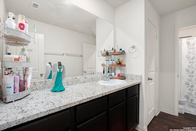 bathroom featuring baseboards, visible vents, wood finished floors, and vanity