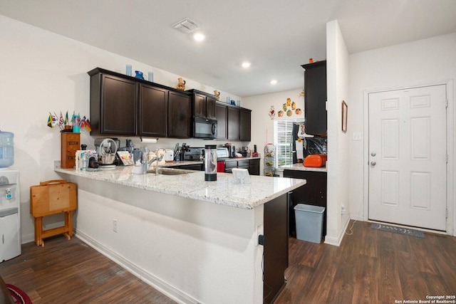 kitchen featuring dark brown cabinetry, black microwave, dark wood-style floors, visible vents, and a peninsula