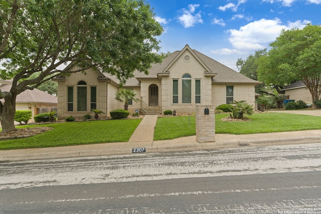 view of front facade with a front lawn, brick siding, and roof with shingles