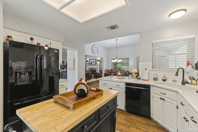 kitchen with wooden counters, visible vents, a sink, black appliances, and white cabinetry