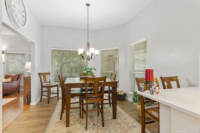 dining area with wood finished floors, baseboards, and a notable chandelier