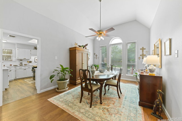 dining space with vaulted ceiling, visible vents, ceiling fan, and light wood-style flooring