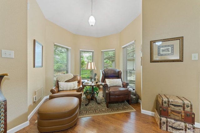 living area with baseboards, wood finished floors, visible vents, and a healthy amount of sunlight