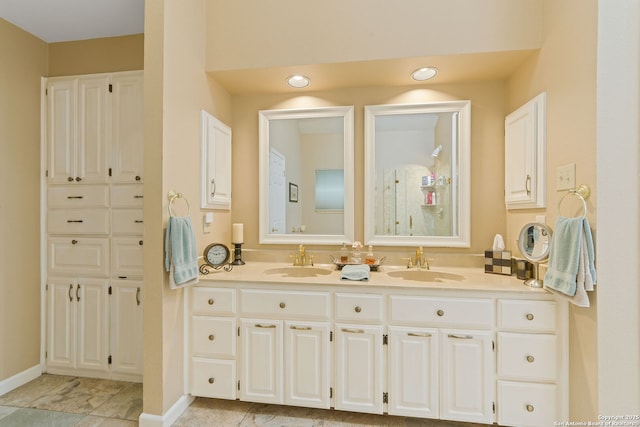 bathroom with tile patterned floors, baseboards, a sink, and double vanity