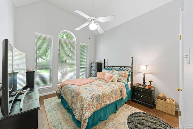 bedroom with baseboards, wood finished floors, high vaulted ceiling, and ceiling fan