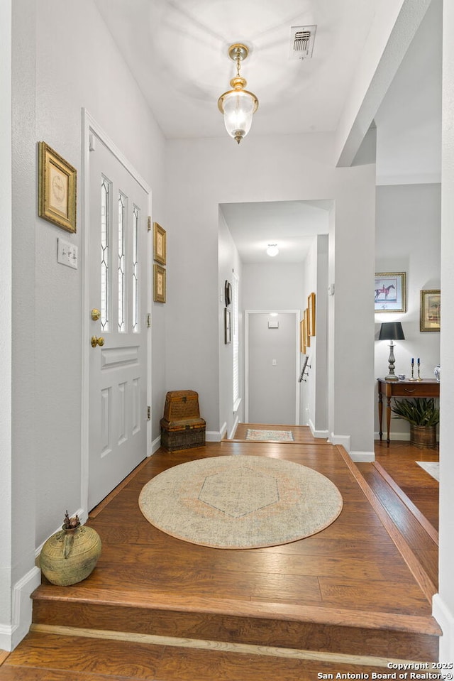 entryway featuring baseboards, wood finished floors, and visible vents