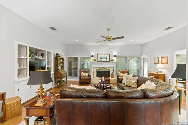 2307 Park Farm, San Antonio, TX 78259 - living room featuring a fireplace with raised hearth, wood finished floors, visible vents, and a ceiling fan