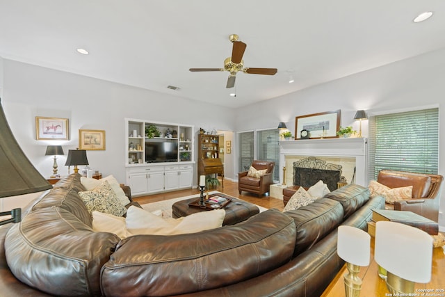 living area featuring a ceiling fan, wood finished floors, a fireplace with raised hearth, visible vents, and recessed lighting
