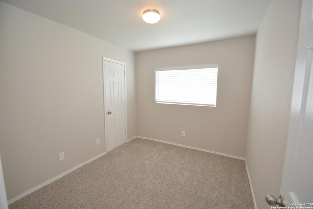 carpeted empty room featuring baseboards