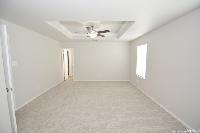 empty room featuring ceiling fan, light carpet, baseboards, and a raised ceiling