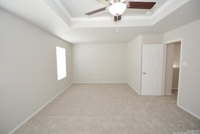 empty room featuring crown molding, ceiling fan, light carpet, a tray ceiling, and baseboards