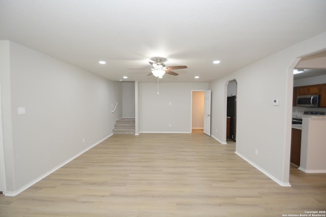 interior space featuring a ceiling fan, arched walkways, recessed lighting, and light wood-style flooring