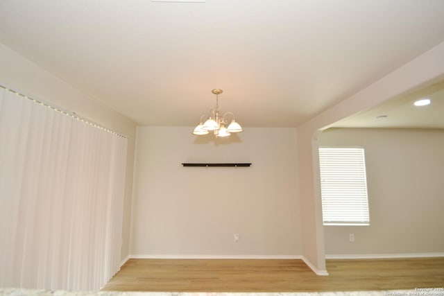 unfurnished room with light wood-type flooring, baseboards, recessed lighting, and a notable chandelier