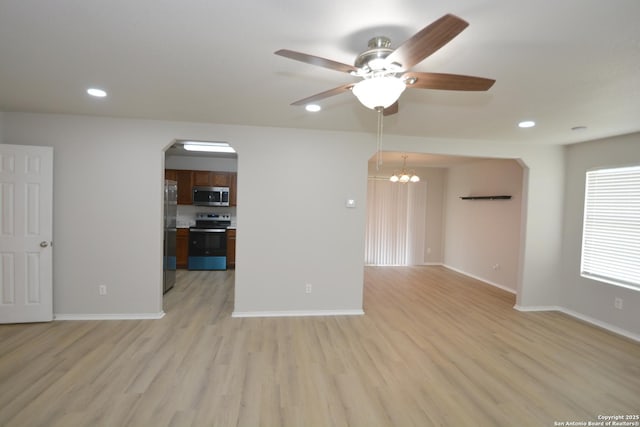 unfurnished living room featuring arched walkways, light wood-style floors, recessed lighting, and ceiling fan with notable chandelier