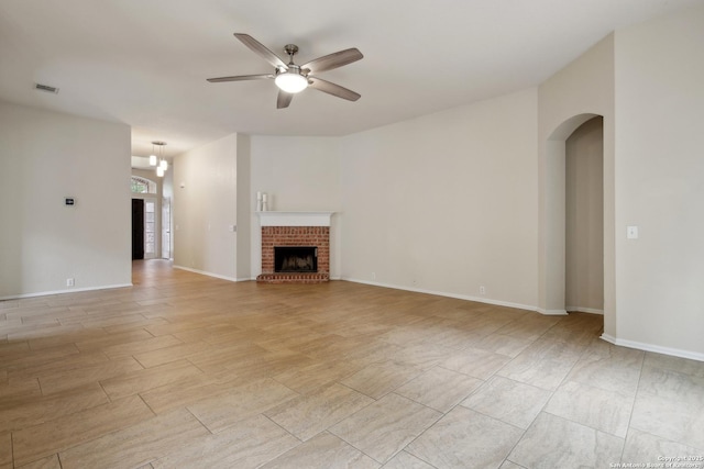 22010 Dolomite, San Antonio, TX 78259 - unfurnished living room featuring visible vents, a brick fireplace, ceiling fan, light wood-type flooring, and arched walkways