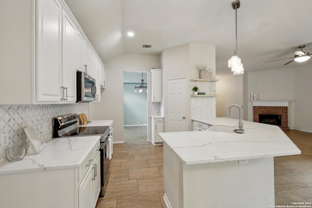kitchen with ceiling fan, appliances with stainless steel finishes, open shelves, open floor plan, and tasteful backsplash
