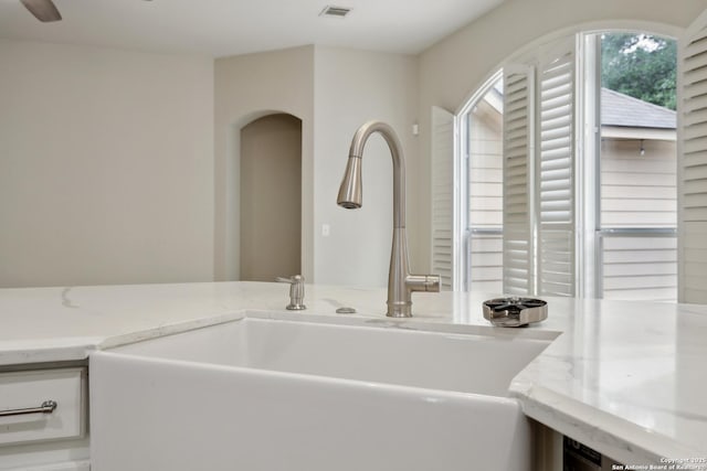 room details featuring a sink, light stone counters, and visible vents