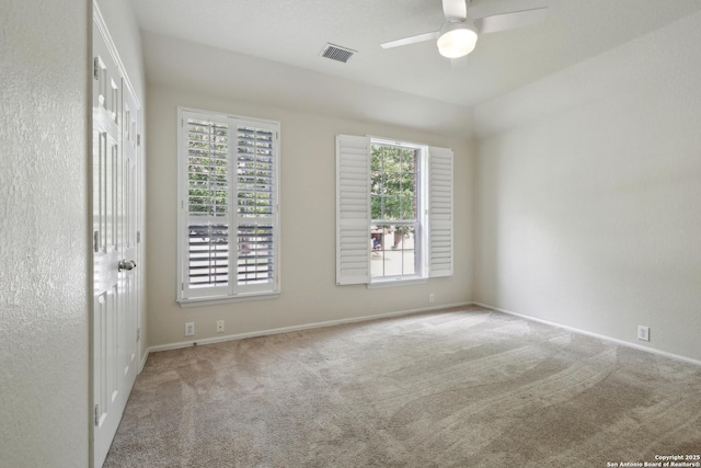 empty room featuring carpet flooring, a ceiling fan, baseboards, and visible vents