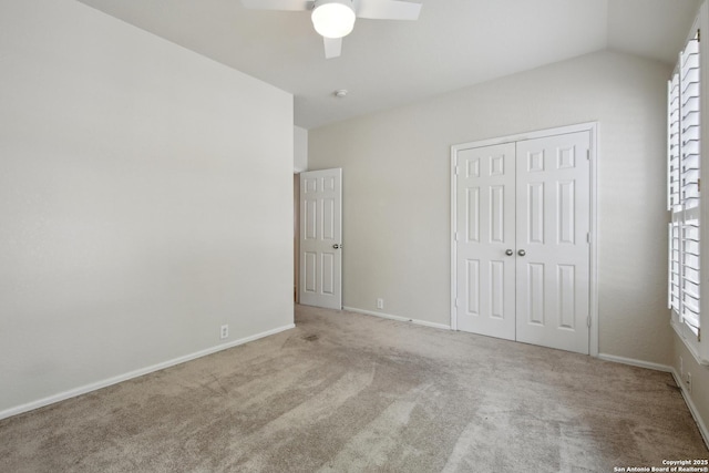 unfurnished bedroom with carpet flooring, baseboards, lofted ceiling, and a closet