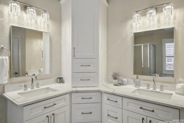 bathroom featuring a sink, a shower stall, and double vanity