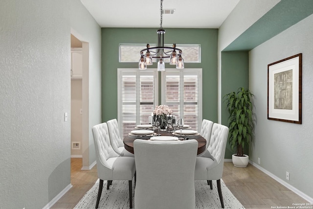 dining room featuring a textured wall, an inviting chandelier, and plenty of natural light