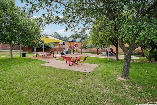 view of home's community with fence, a yard, and playground community