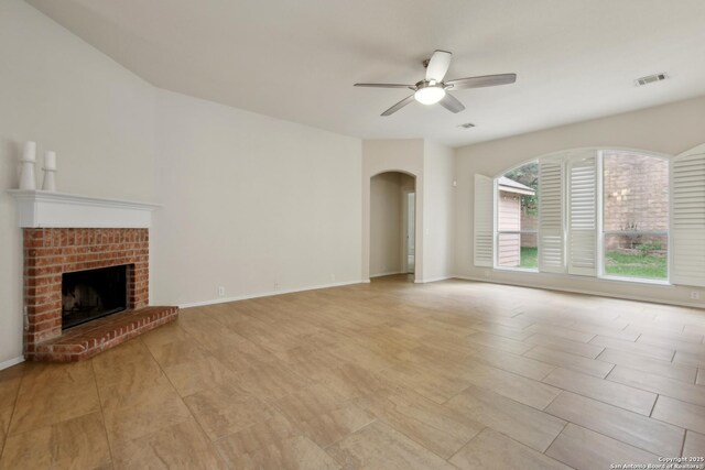 22010 Dolomite, San Antonio, TX 78259 - unfurnished living room with a ceiling fan, visible vents, arched walkways, a brick fireplace, and baseboards