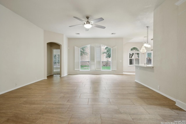 22010 Dolomite, San Antonio, TX 78259 - unfurnished living room featuring arched walkways, baseboards, visible vents, and ceiling fan with notable chandelier