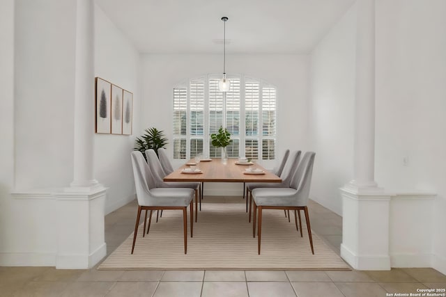 dining room featuring light tile patterned floors, baseboards, and ornate columns