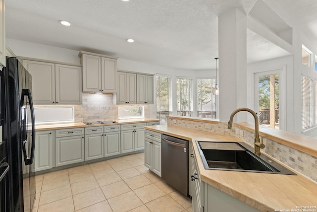 kitchen featuring freestanding refrigerator, dishwasher, tasteful backsplash, and a sink