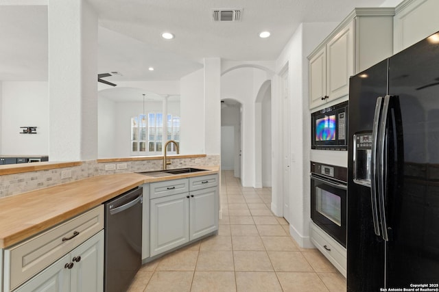 kitchen with decorative backsplash, butcher block counters, a sink, and black appliances