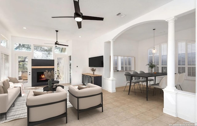 living room featuring a lit fireplace, ornate columns, visible vents, and ceiling fan