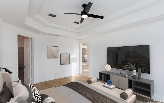 bedroom with a tray ceiling, wood finished floors, and visible vents