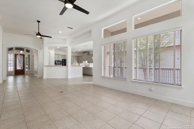 unfurnished living room with a ceiling fan, light tile patterned floors, and a healthy amount of sunlight