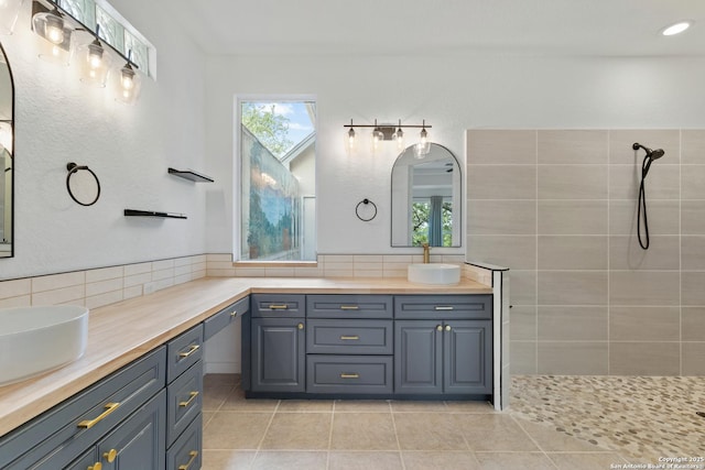 full bath with a tile shower, tasteful backsplash, tile patterned flooring, and vanity