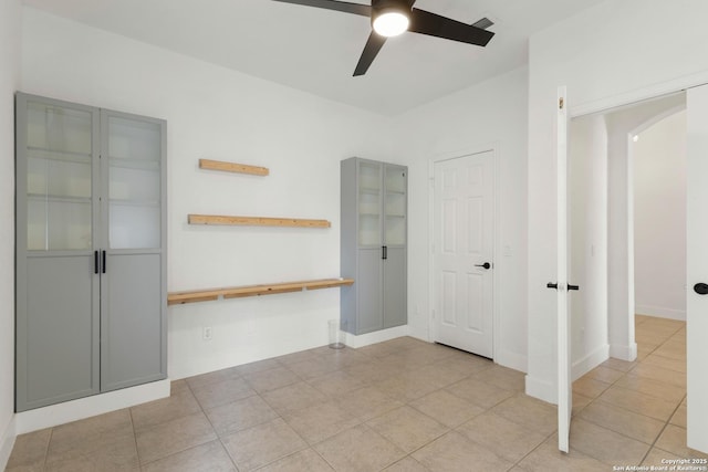 unfurnished bedroom with ceiling fan, baseboards, and light tile patterned floors
