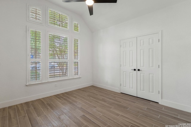 unfurnished bedroom with ceiling fan, lofted ceiling, wood finished floors, and baseboards