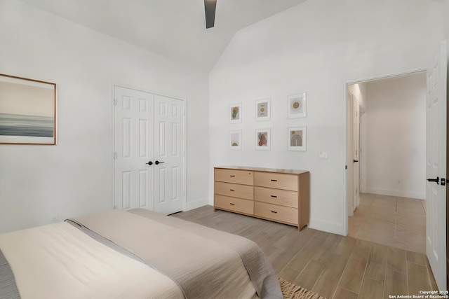 bedroom with vaulted ceiling, a closet, light wood-type flooring, ceiling fan, and baseboards