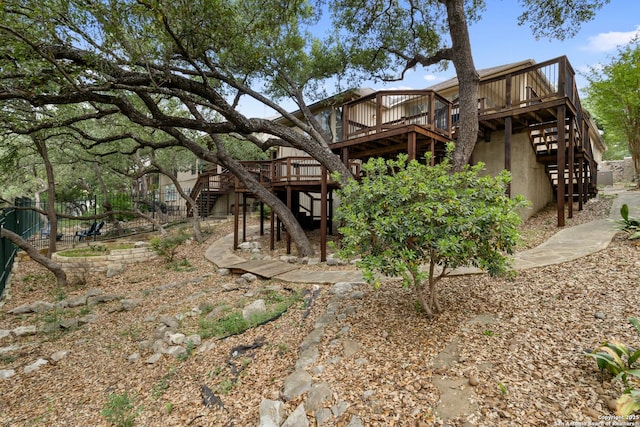back of house featuring stucco siding, a wooden deck, fence, and stairs