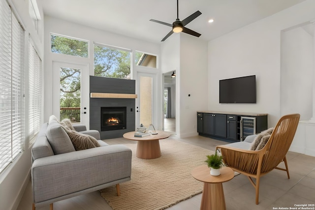 living area with baseboards, a warm lit fireplace, recessed lighting, and ceiling fan