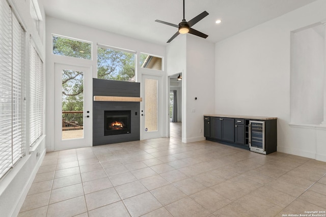 unfurnished living room featuring a warm lit fireplace, light tile patterned flooring, ceiling fan, wine cooler, and recessed lighting
