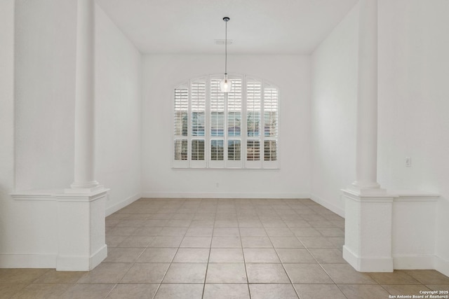 unfurnished dining area featuring light tile patterned floors, baseboards, and ornate columns