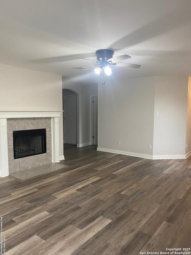 853 Satellite Vw, Round Rock, TX 78665 - unfurnished living room featuring ceiling fan, arched walkways, dark wood-type flooring, baseboards, and a fireplace