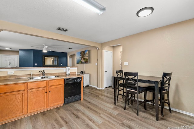 kitchen with dishwasher, a sink, visible vents, and light wood-style flooring