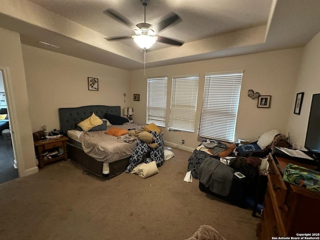 bedroom with a raised ceiling, carpet flooring, baseboards, and ceiling fan