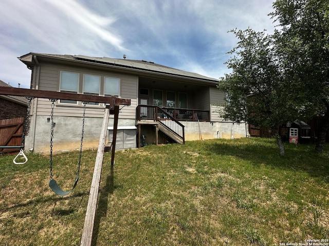 back of property featuring a lawn, solar panels, and fence